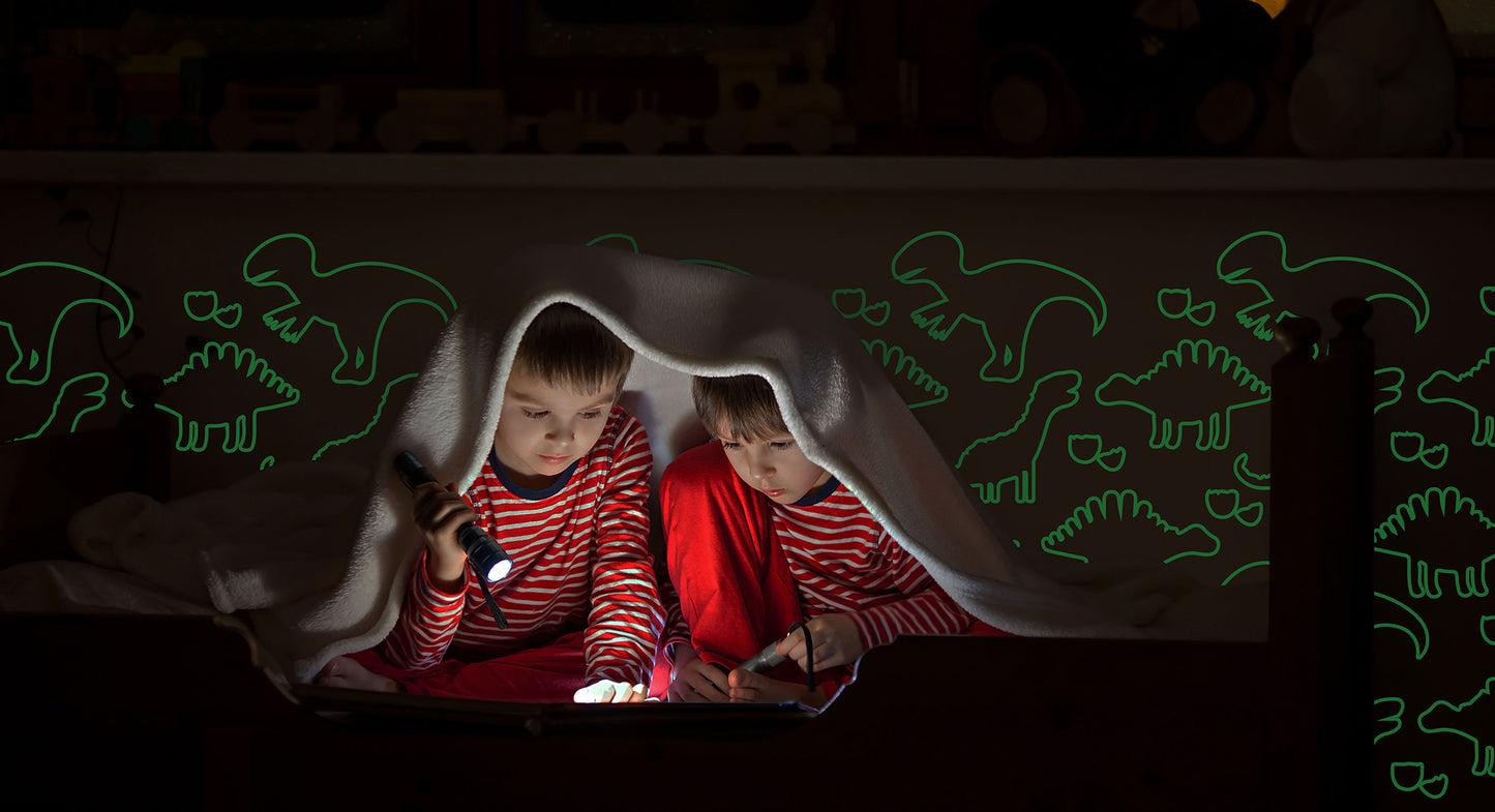 boys reading under the covers and dinosaurs on the wall 