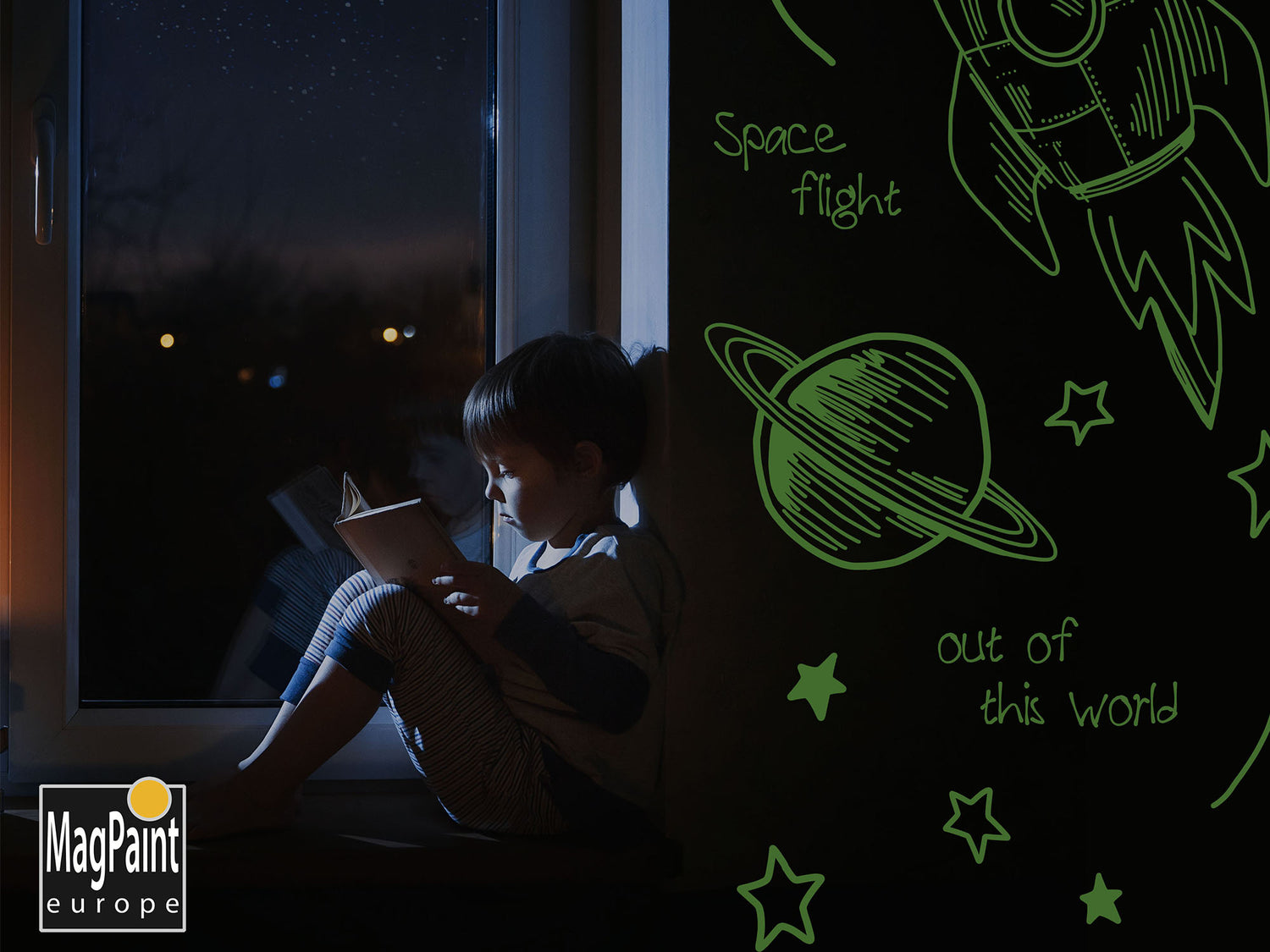 Boy sat reading with Glowpaint on the wall next to him
